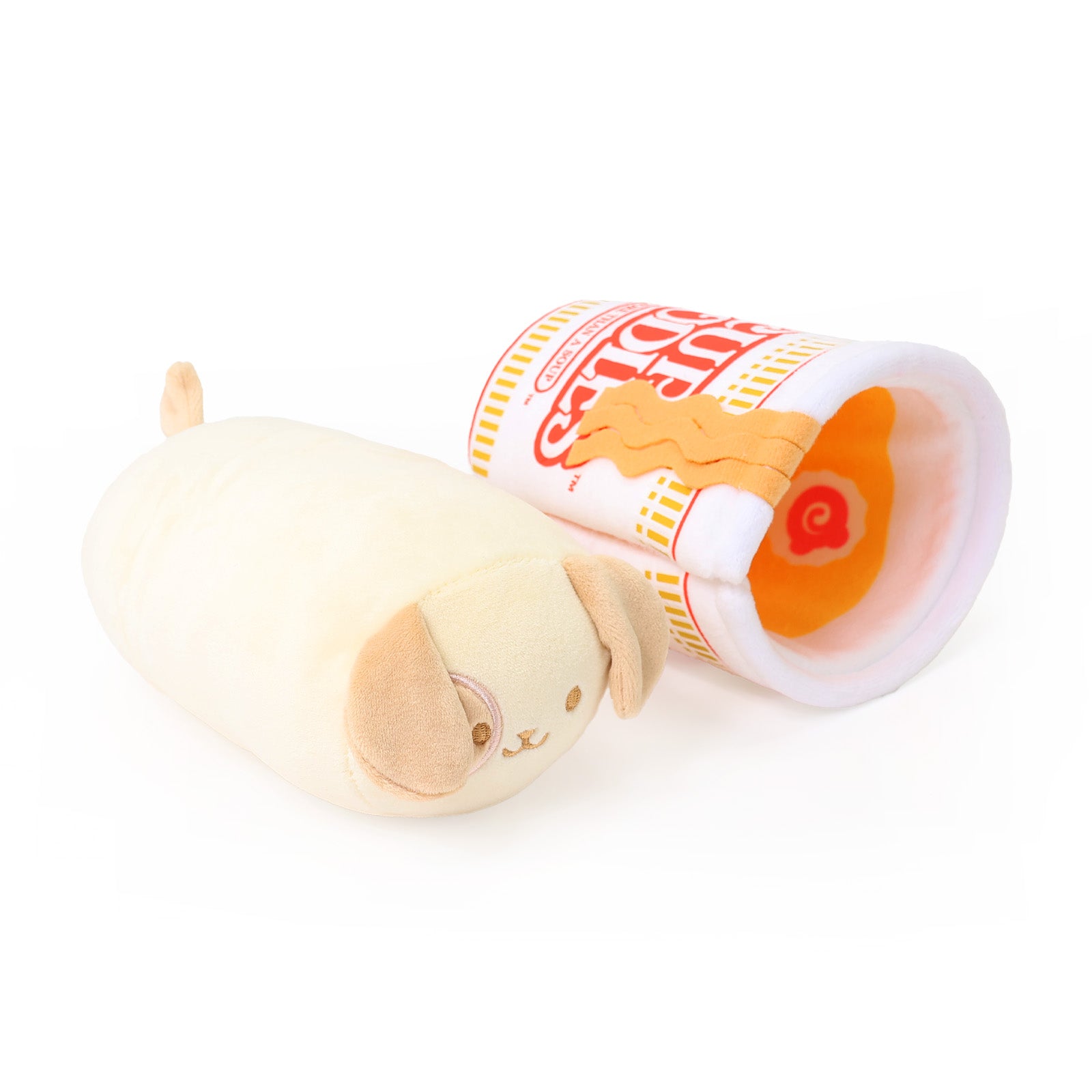 Cream-colored dog Puppiroll plush toy lying next to a Cup Noodles-themed plush cup tipped on its side, revealing orange noodle and narutomaki toppings inside, on a white background.